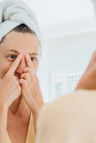 Woman looking herself on mirrow checking the results of her custom skincare routine