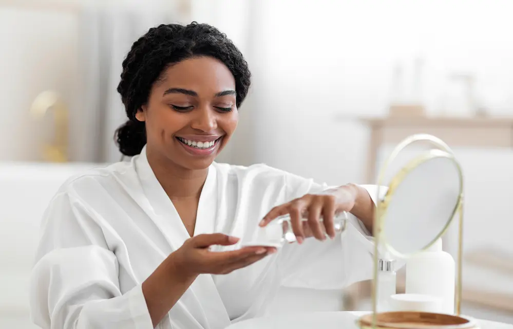 Smiling Black Female Applying Ferulic Acid For Skin Routine